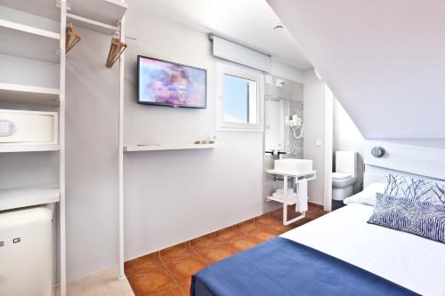 a bedroom with a bed and a tv on the wall at Ryans Pocket in Ibiza Town