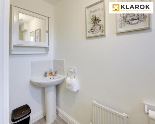 een witte badkamer met een wastafel en een spiegel bij LARGE 4 Bedroom Semi-Detached House Sleeps 7 By Klarok Short Lets & Serviced Accommodation in Peterborough