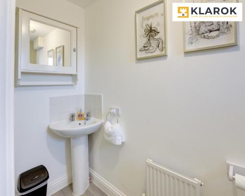 Un baño blanco con lavabo y espejo. en LARGE 4 Bedroom Semi-Detached House Sleeps 7 By Klarok Short Lets & Serviced Accommodation, en Peterborough