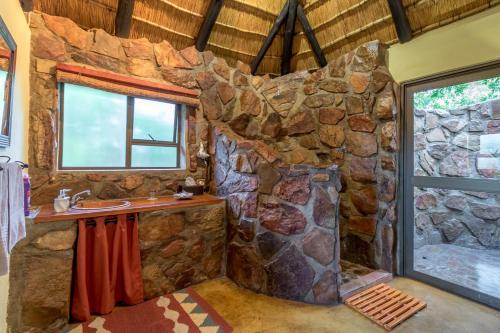 a stone bathroom with a sink and a shower at Iketla Lodge in Ohrigstad