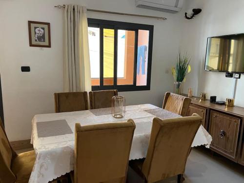 a dining room with a table and chairs and a television at TérangaLux Appartement Le Yoruba Dakar Sacré Cœur 3 in Dakar