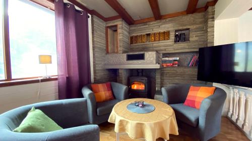 a living room with two chairs and a table and a fireplace at Storfossen Hostel in Gratangen