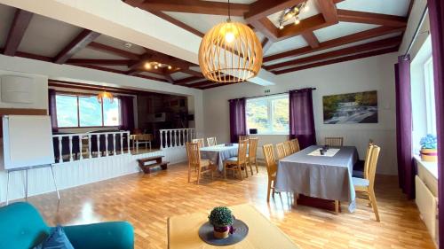 a living room with tables and chairs and a chandelier at Storfossen Hostel in Gratangen