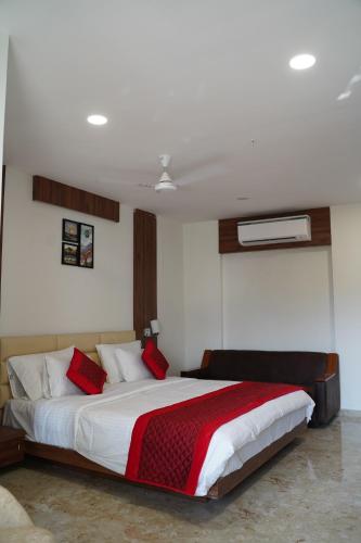 a bedroom with a large bed with red pillows at LEELA BIZOTEL in Junagadh