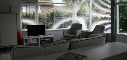 a living room with a couch and two chairs and a television at Rekerlanden 90 in Schoorldam