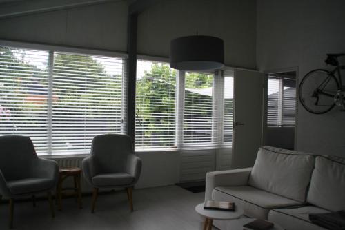 a living room with a couch and chairs and windows at Rekerlanden 90 in Schoorldam