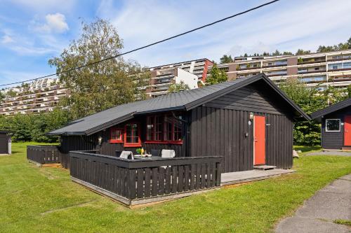 a black building with red doors on a yard at Topcamp Bogstad - Oslo in Oslo