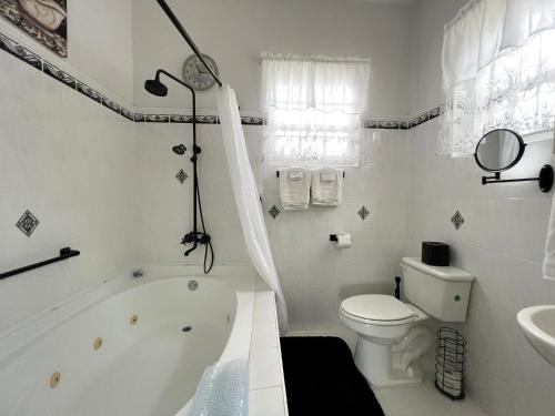 a white bathroom with a tub and a toilet and a sink at Welcome to the unpretentious and breezy Graceville, steps away from the beach in Saint James