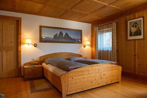 ein Schlafzimmer mit einem Holzbett in einem Zimmer in der Unterkunft Rodahof in Sexten