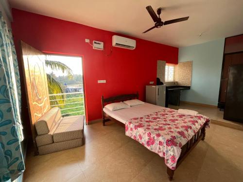 um quarto com uma cama e uma parede vermelha em Morjim Guest House em Morjim