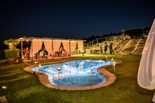 a swimming pool at night with people standing around it at Essenziale in Castell’Anselmo