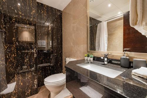 a bathroom with a toilet and a sink and a mirror at Daniels Studio Elite Downtown Partial Burj Khalifa View in Dubai