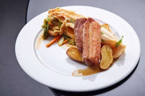 a plate of food with meat and vegetables on a table at ESE HOTEL in Birštonas