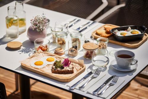 a table with a breakfast of eggs and bread at ESE HOTEL in Birštonas