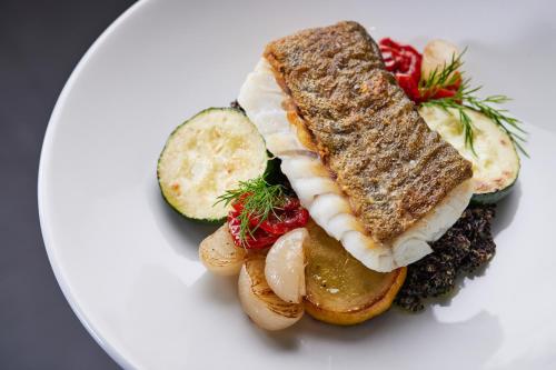 a white plate with a sandwich and vegetables on it at ESE HOTEL in Birštonas