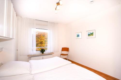 um quarto branco com uma cama e uma janela em Hanseat II Whg 147 em Grömitz