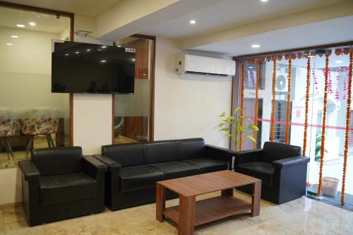 a living room with a couch and a table and a tv at LEELA BIZOTEL in Junagadh