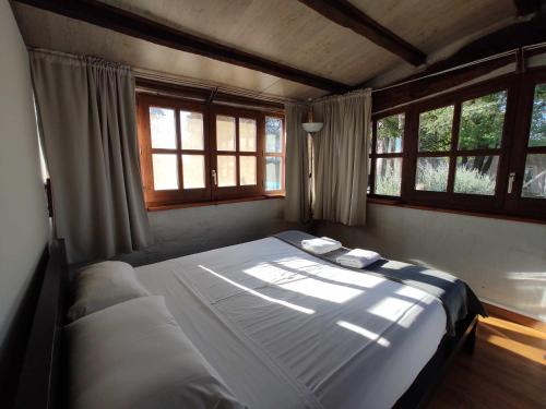 un grande letto in una stanza con finestre di Casita con jacuzzi Rectoria de Dosquers a Maia de Montcal