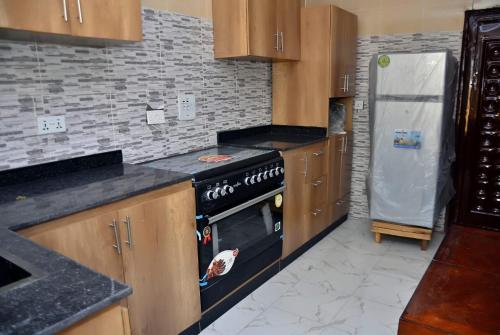 a kitchen with a stove and a refrigerator at Frankie’s Place: A spacious 4-bedroom home in Ondo