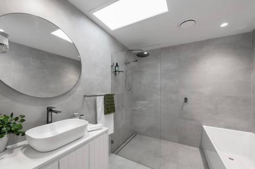 a bathroom with a shower and a sink and a mirror at Two Dreamy Properties In One in Culburra Beach