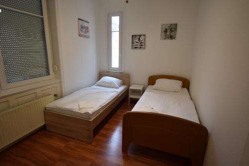 two beds in a small room with two windows at Wasen Apartment in Stuttgart