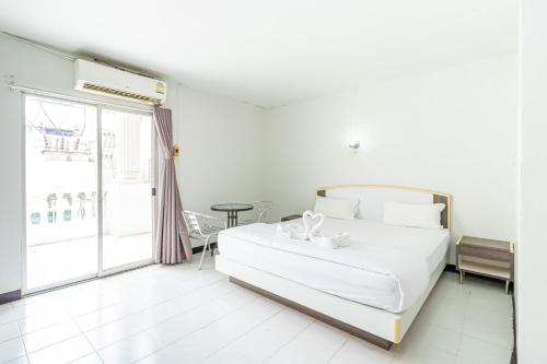 a white bedroom with a bed and a table at Boonchai Mansion in Hat Yai