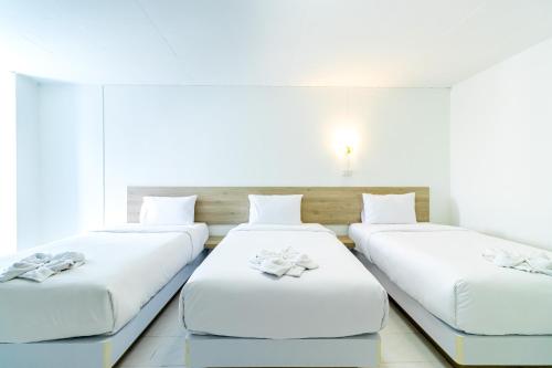 three beds in a room with white walls at Boonchai Mansion in Hat Yai