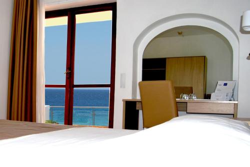 a bedroom with a bed and a view of the ocean at Hotel Fontane Bianche in Fontane Bianche