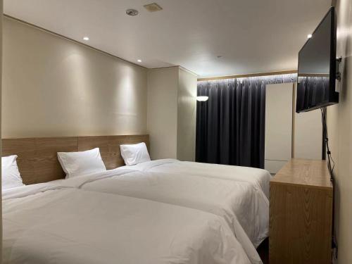 a bedroom with two beds and a flat screen tv at The garden hotel in Seoul