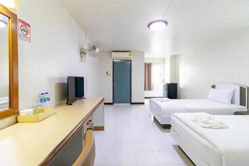 a hotel room with two beds and a tv at Boonchai Mansion in Hat Yai