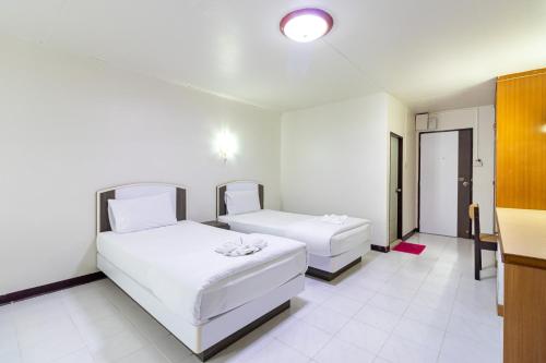 two beds in a room with white walls and white floors at Boonchai Mansion in Hat Yai