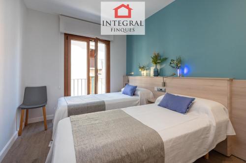 two beds in a hotel room with blue walls at Palamós Exclusive Apartments in Palamós