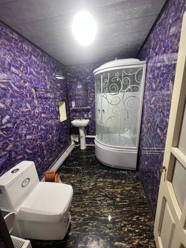 a purple bathroom with a toilet and a sink at MOHINUR Hostel in Bukhara
