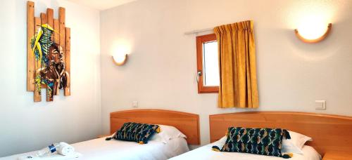 a bedroom with two beds and a window at Hotel La Bosselle in Saint-Philbert-de-Grand-Lieu