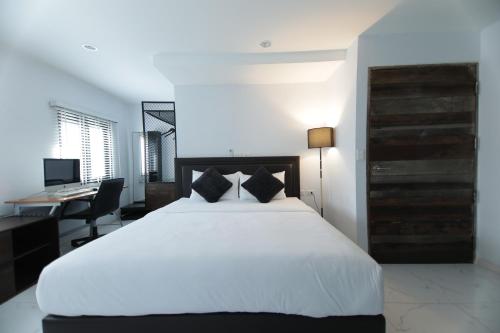 a bedroom with a large white bed and a desk at WiRE BANGKOK PRAKHANONG in Amphoe Phra Khanong