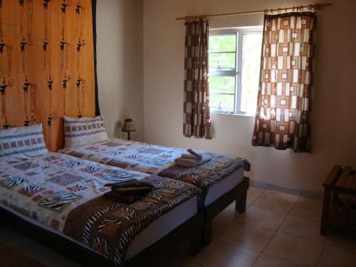 a bedroom with a bed and a window with curtains at Okambishi's Rest in Usakos