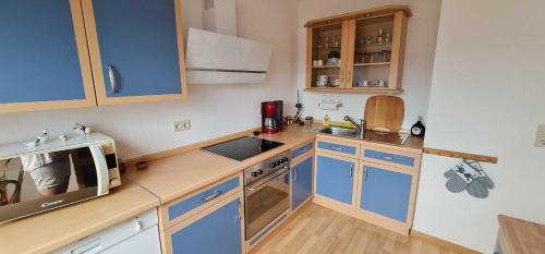 a small kitchen with blue cabinets and a microwave at Ferienwohnung Vennen in Görlitz