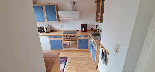 a small kitchen with blue cabinets and a wooden floor at Ferienwohnung Vennen in Görlitz