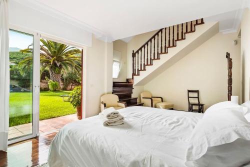 Un dormitorio blanco con una cama grande y una escalera en Villa Artigar, garden, swimming pool and bbq., en Puerto de la Cruz