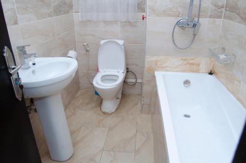 a bathroom with a toilet and a sink and a tub at Residency Hotel Area11 Garki Abuja in Abuja