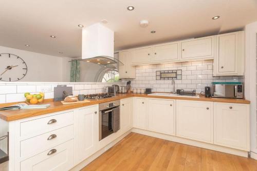 una cocina con armarios blancos y un reloj en la pared en Panda Sanctuaries, Kensington Chapel Apartment, en Bath