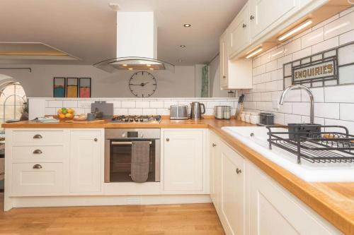 eine Küche mit weißen Schränken und einer Uhr an der Wand in der Unterkunft Panda Sanctuaries, Kensington Chapel Apartment in Bath