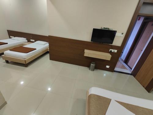 a room with two beds and a flat screen tv at Hotel Midtown Inn in Trimbak