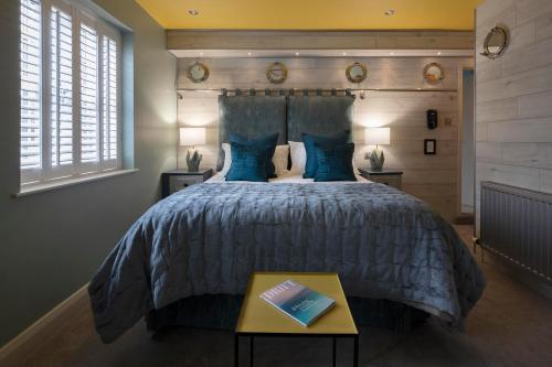 a bedroom with a large bed with blue pillows at Talland Bay Hotel, Looe in Talland