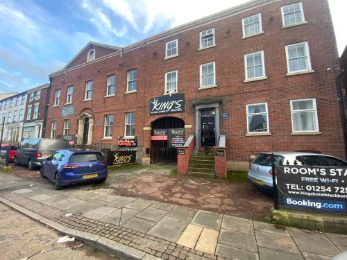 un edificio de ladrillo con coches estacionados frente a él en Kings Hotel Blackburn, en Blackburn