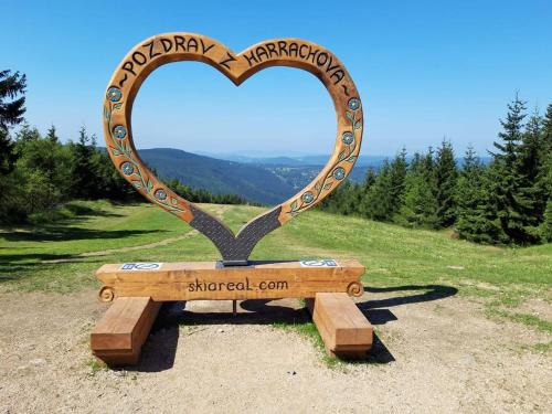 a heart sign on a bench in a field at ENJOYHARRACHOV - Atraktivní klidný klimatizovaný apartmán 20 v centru Harrachova s parkováním, Wifi-WLAN, SAT, herní konzolí, Ipad, Netflix zdarma, možností dobíjení auta, výhledem do zahrady a na romantický kostelík in Harrachov