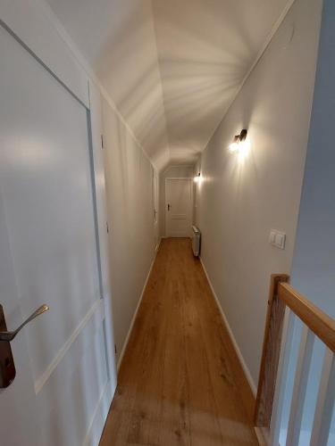 an empty hallway with a white wall and wooden floors at Dom przy lesie in Zawadka