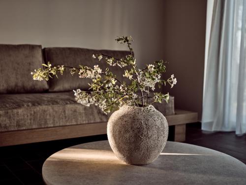 a vase with flowers on a table in front of a couch at Zayn Luxury Villas, a Serene Escape, By ThinkVilla in Zakynthos Town