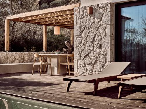 a patio with a bench next to a stone wall at Zayn Luxury Villas, a Serene Escape, By ThinkVilla in Zakynthos Town