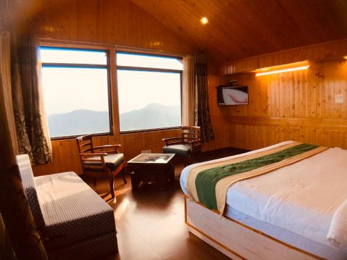 een slaapkamer met een bed, een stoel en een raam bij The Himalayan Escape in Mundaghat 